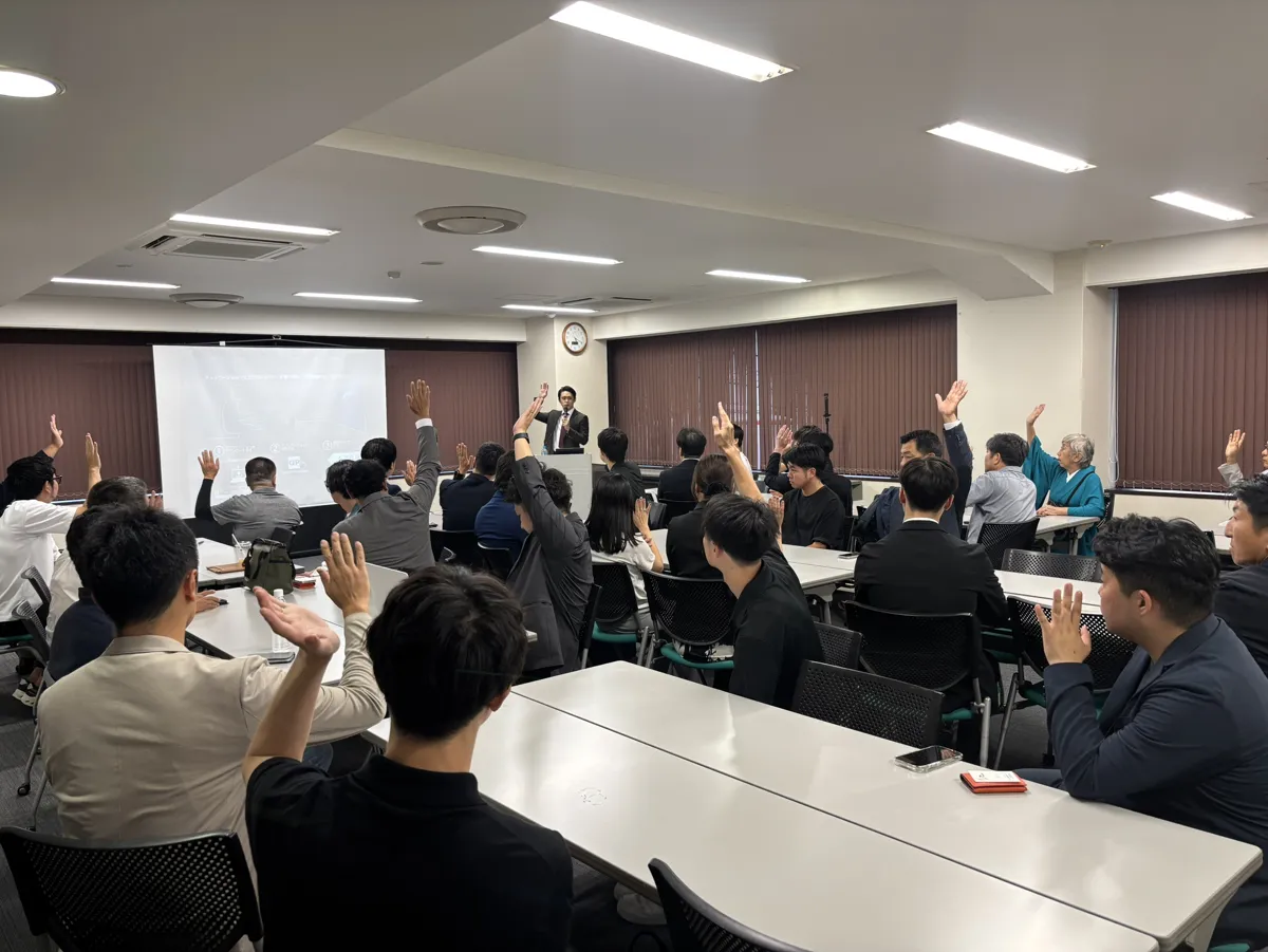 交流会の会場で手を挙げて答える参加者たち
